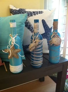 three decorative bottles are sitting on a table next to two pillows and one is wrapped in twine