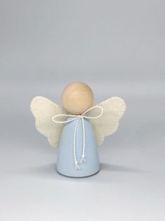 a small angel figurine with white wings and a blue body on a gray background