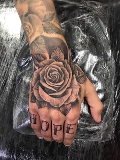 a person's hand with a rose on it and the word hope written in black ink