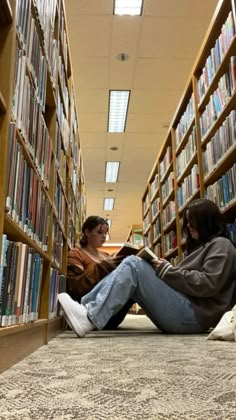 two women sitting on the floor in front of bookshelves