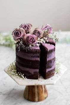 a chocolate cake with purple frosting and flowers on top is cut in half to show the inside