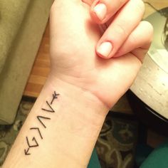 a woman's wrist with the word faith written on it and an arrow tattoo