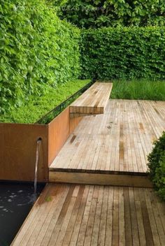 a wooden deck with water running from it and some bushes in the backround