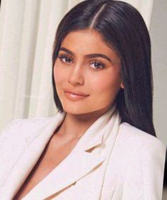 an image of a woman with long black hair wearing a white suit and posing for the camera