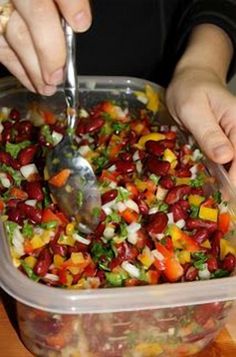 a person scooping food out of a plastic container with a metal spoon in it