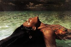 a woman floating in the ocean with her head above the water's surface and dark clouds overhead