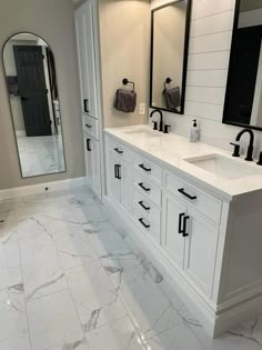 a large bathroom with marble floors and white cabinets in the center, along with two sinks