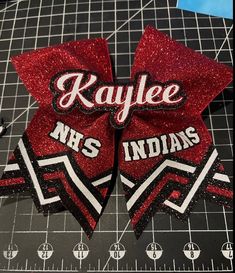 a pair of red and black hair bows with the name kaylee n s indians on it