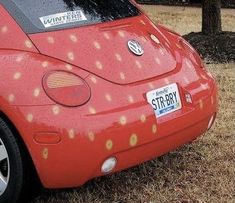 a red vw bug parked in the grass with yellow dots on it's side