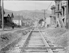 an old black and white photo of a train track in the middle of some town