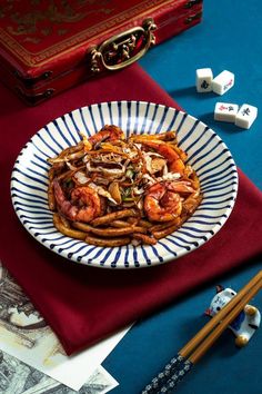 a white and blue plate topped with pasta next to diced dominos on top of a table