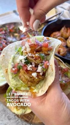 a person is holding up a taco with shrimp and lettuce on it