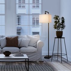 a living room with a couch, table and lamp in front of large open windows