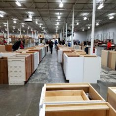 people are walking through an empty warehouse with lots of unfinished cabinets on the floor and walls