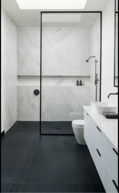 a white bathroom with black tile flooring and an open skylight above the toilet