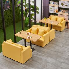 yellow chairs and tables in a room with artificial grass on the walls, plants behind them