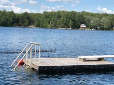 there is a boat dock on the water with steps leading to it and trees in the background