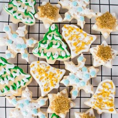 several decorated cookies on a cooling rack with gold and white frosting, including christmas trees