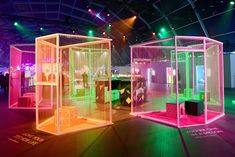 three different colored cages are on display in a room with green and pink lights around them