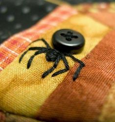 a black spider sitting on top of a yellow and red plaid pillow with a button