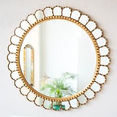 a round mirror hanging on the wall next to a potted plant in a living room