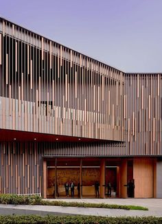 two people standing in front of a building with wooden slats on the facade and doors