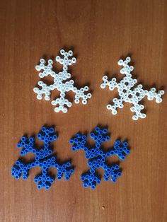 three pieces of plastic beaded snowflakes on a wooden surface