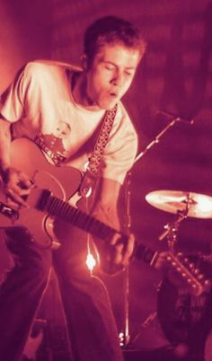 a man playing guitar in front of a microphone