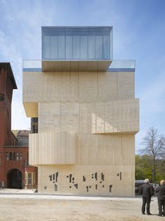 two people are standing in front of a building that looks like it is made out of concrete