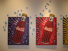 three paintings hanging on the wall with bubbles coming out of them and one has a coca - cola bottle painted on it