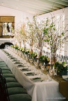 a long table is set with wine glasses and place settings for the guests to sit at