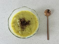 a glass bowl filled with food next to a spoon