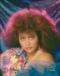 an old photo of a woman with pink hair and blue dress holding flowers in her hands