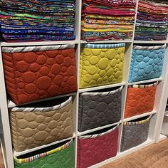 the closet is filled with many different colored fabrics and fabric storage bins on shelves