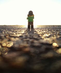 a small toy is standing in the middle of an empty road with sun shining on it