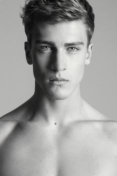 black and white photograph of a shirtless young man with short hair looking at the camera