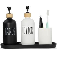 three bottles with toothbrushes, soap and lotion sitting on a black tray