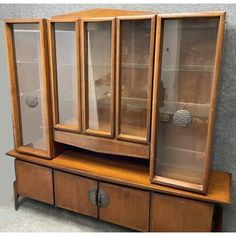 a wooden cabinet with glass doors and drawers