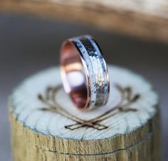 two wedding bands sitting on top of a piece of wood with an arrow in the middle