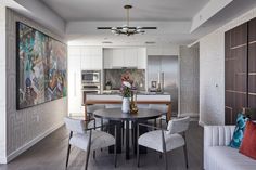 a dining room table with chairs around it in front of a kitchen and living room