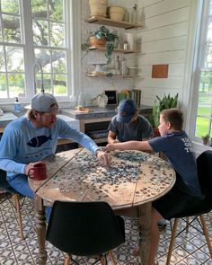 three people sitting at a table with puzzles on it