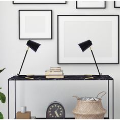 two black lamps are on top of a table next to some books and a clock