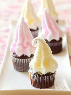 four cupcakes with white frosting and pink icing on a long plate