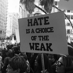 black and white photo of protestors holding sign that reads hate is a choice of the weak