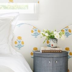 a nightstand with flowers and books on it