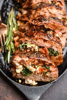 grilled pork chops and vegetables on a black plate with a fork next to it