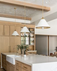 a large kitchen with wooden cabinets and white counter tops, two pendant lights over the island