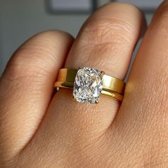 a woman's hand with a gold ring and a diamond in the middle, on top of her finger