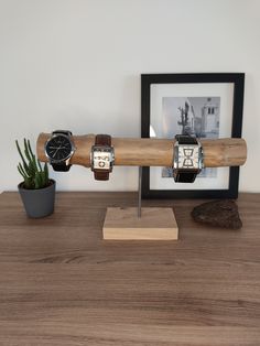 two wooden watch stands on a table next to a potted plant and framed photograph