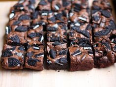 brownies with oreo cookies and white chocolate chips are on a cutting board, ready to be eaten